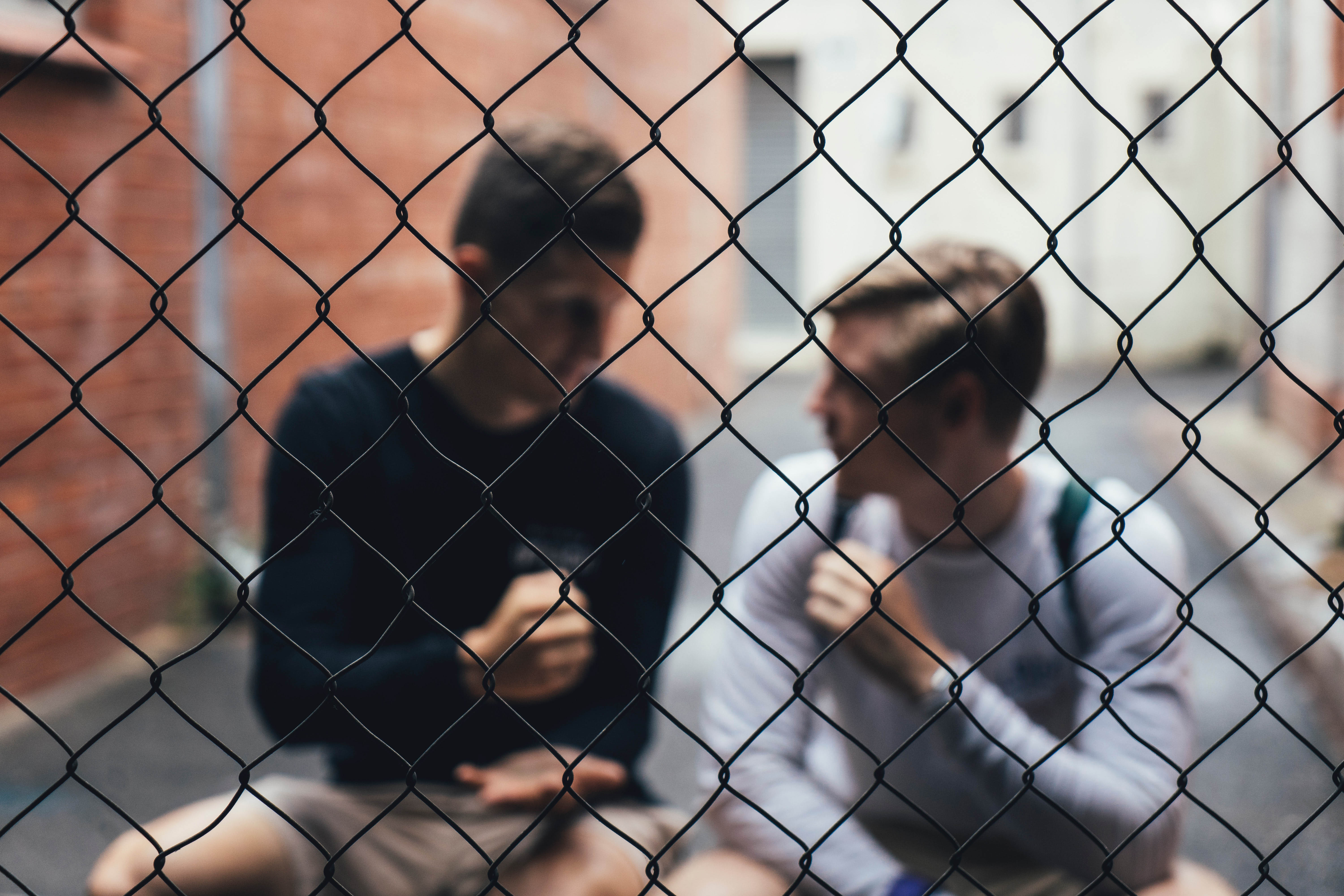 two guys sitting behind wire fence