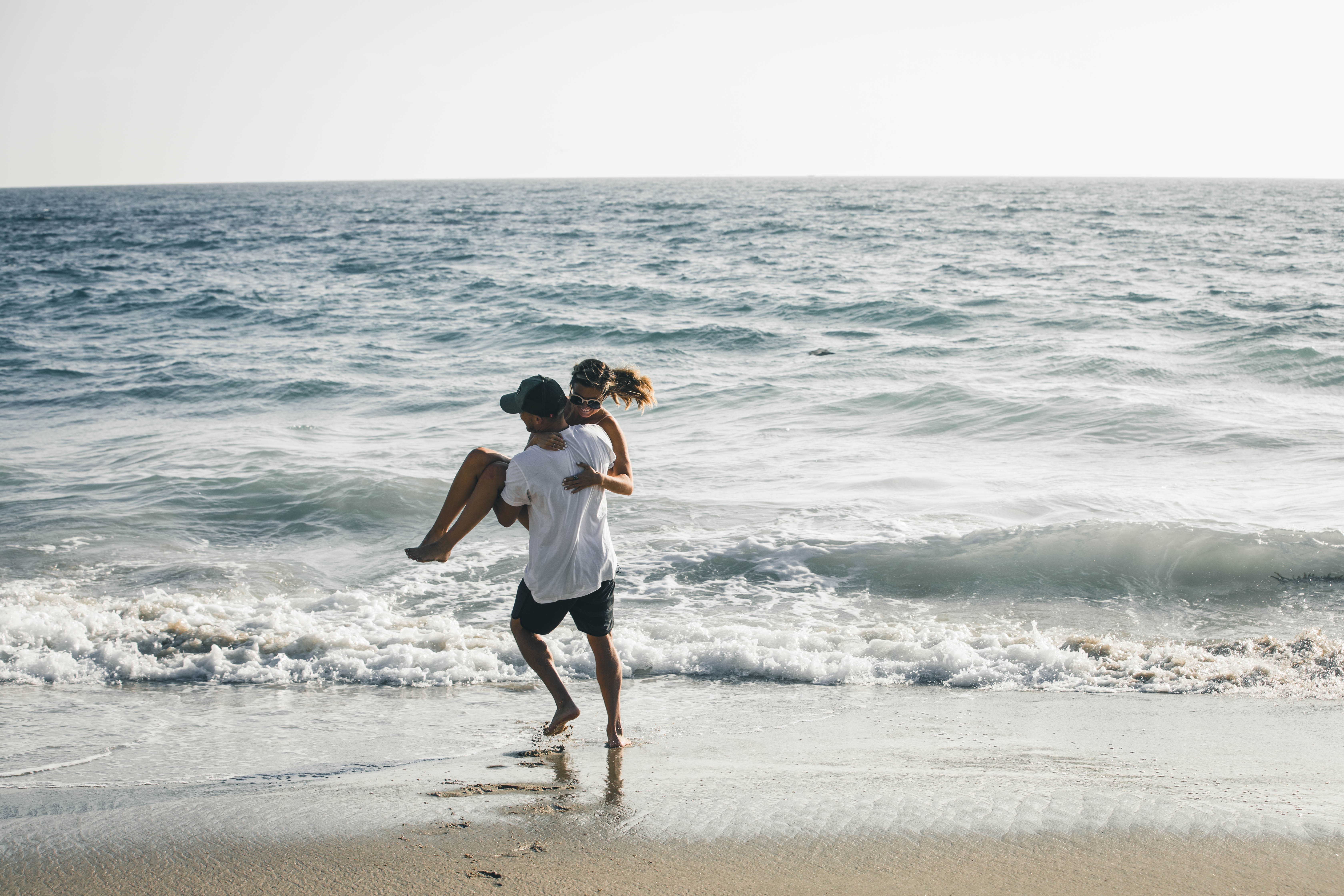 Man carries woman to the sea on the beach