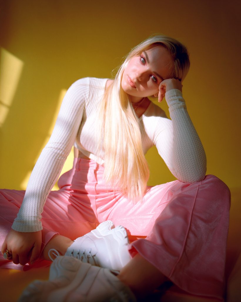 Sody sitting on the floor with white trainers and pink trousers