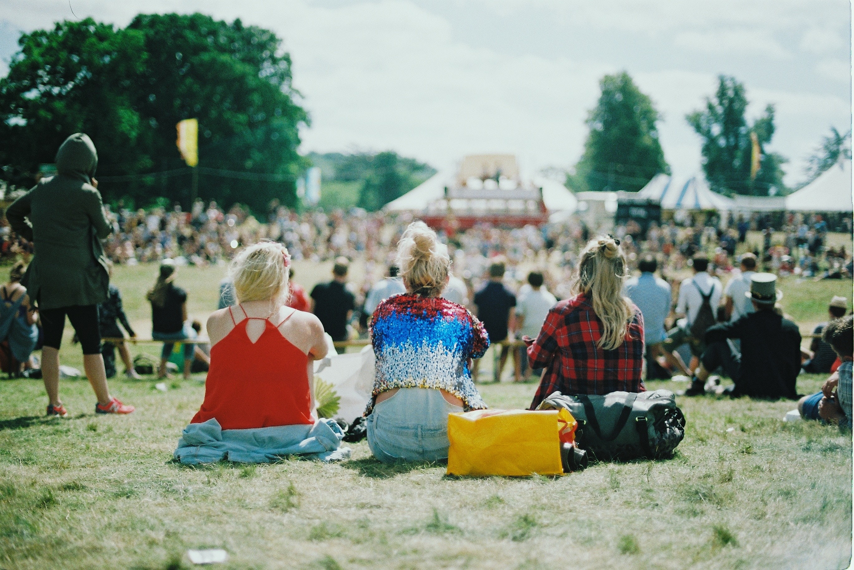 A group of people on grass field on a sunny day at a festival.