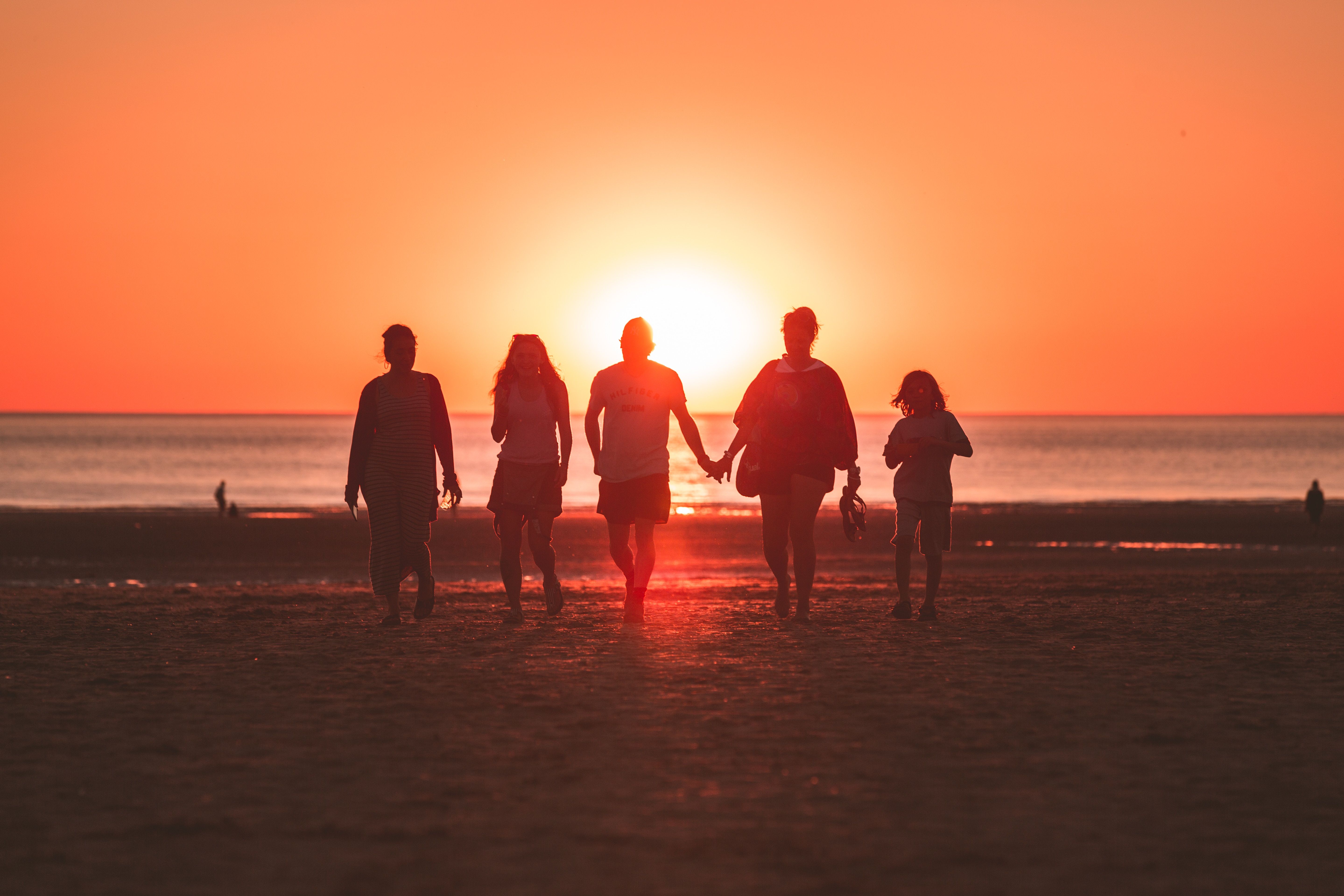 Family and Friends walking on the beach at sunset.