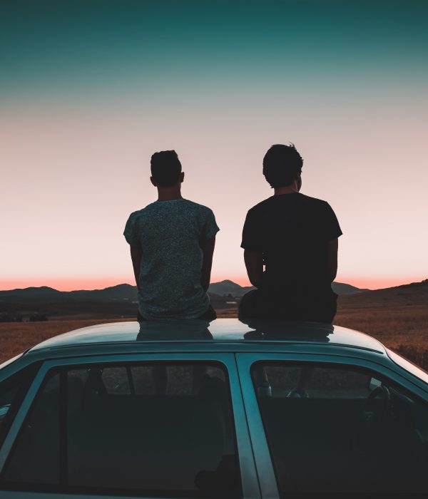 Two men sat on a car roof.